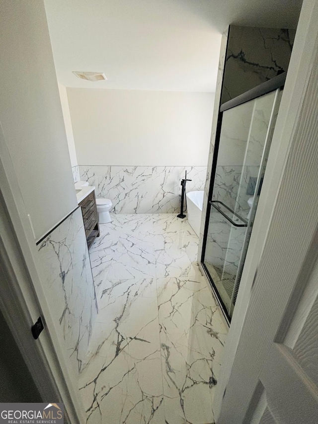 bathroom featuring a marble finish shower, toilet, marble finish floor, a freestanding bath, and vanity