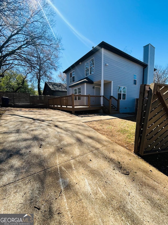 view of property exterior featuring fence and a wooden deck