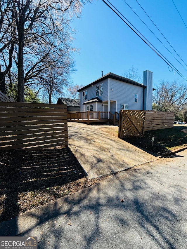 view of side of property with driveway and a wooden deck