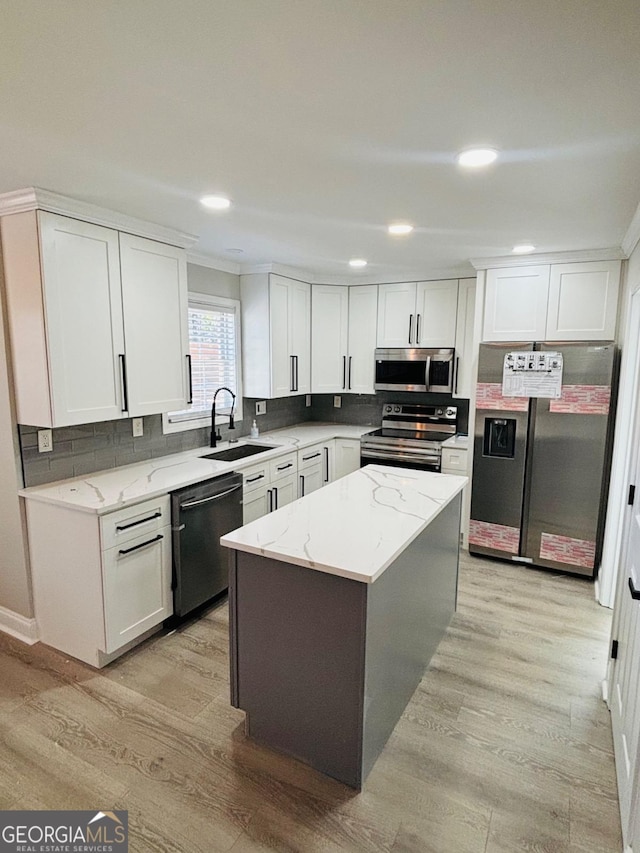 kitchen featuring appliances with stainless steel finishes, light wood-style floors, white cabinetry, and a sink