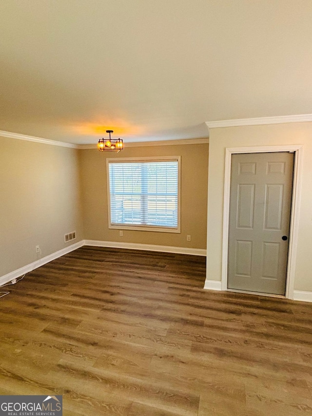 unfurnished room with visible vents, crown molding, baseboards, and wood finished floors