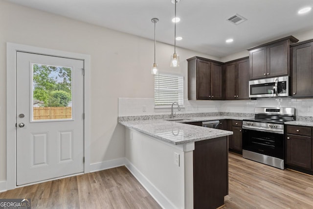 kitchen featuring visible vents, decorative backsplash, dark brown cabinetry, a sink, and appliances with stainless steel finishes