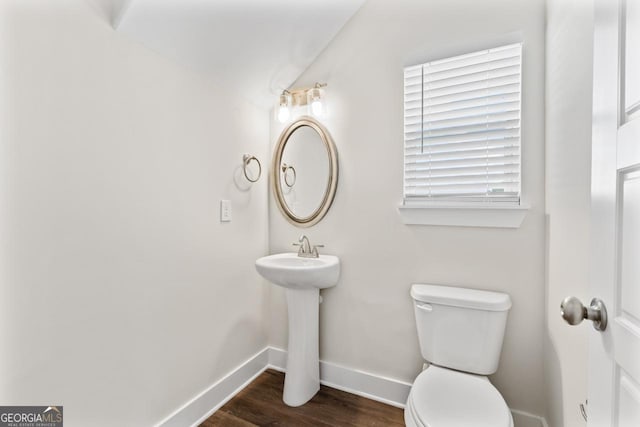 half bathroom featuring toilet, baseboards, wood finished floors, and lofted ceiling