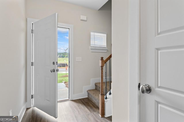 foyer with stairway, baseboards, and wood finished floors