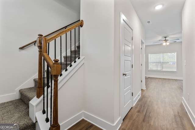 staircase featuring baseboards, ceiling fan, wood finished floors, and visible vents