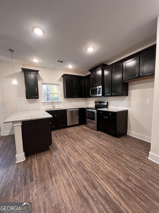 kitchen featuring visible vents, dark wood-style floors, dark cabinets, a peninsula, and stainless steel appliances