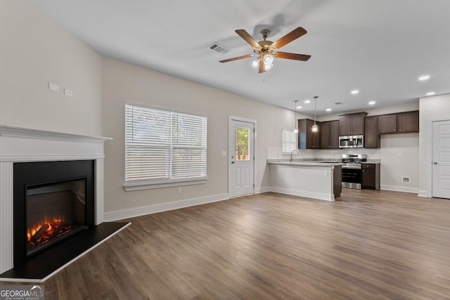 unfurnished living room with a glass covered fireplace, a ceiling fan, recessed lighting, wood finished floors, and visible vents