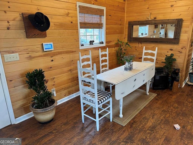 dining room featuring wood walls, wood finished floors, and baseboards