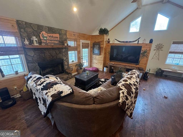 living area featuring wood walls, a fireplace, high vaulted ceiling, and hardwood / wood-style flooring