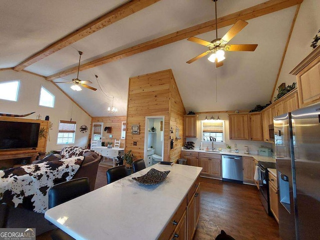 kitchen featuring a center island, light countertops, appliances with stainless steel finishes, open floor plan, and beamed ceiling