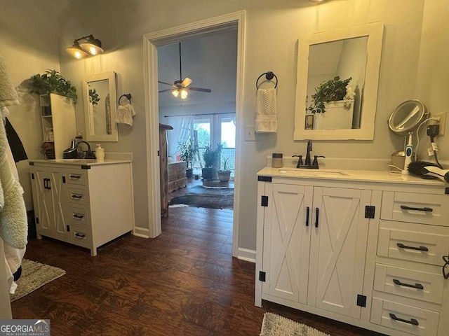 bathroom featuring ceiling fan, wood finished floors, two vanities, and a sink