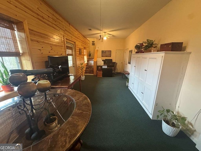 living room with lofted ceiling, carpet, wooden walls, and a ceiling fan