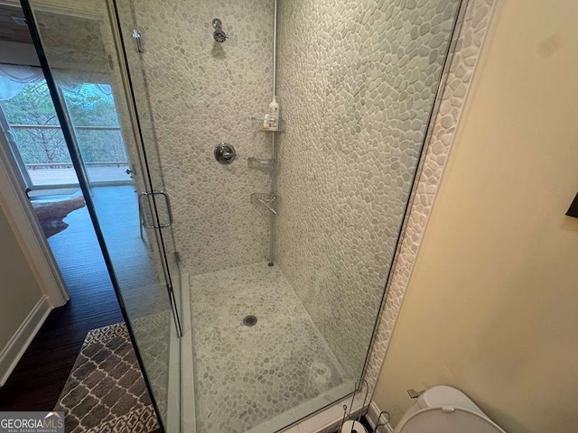 bathroom featuring toilet, a stall shower, and wood finished floors