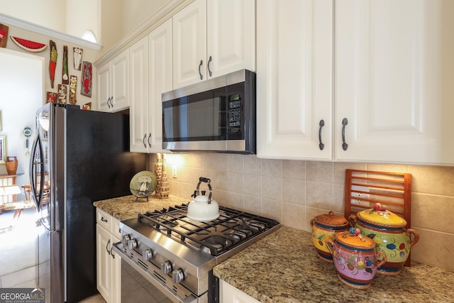 kitchen with appliances with stainless steel finishes, white cabinetry, backsplash, and light stone countertops