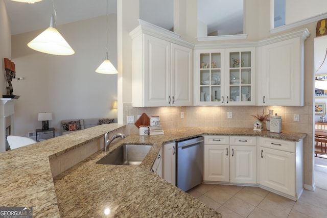 kitchen with stainless steel dishwasher, a sink, light stone counters, and white cabinetry