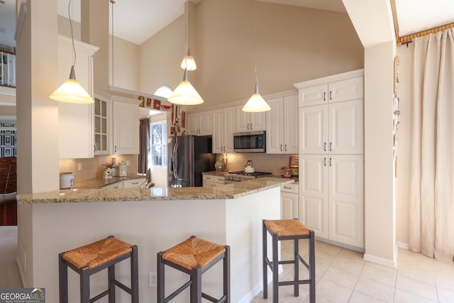 kitchen with stainless steel microwave, high vaulted ceiling, black refrigerator with ice dispenser, backsplash, and a breakfast bar