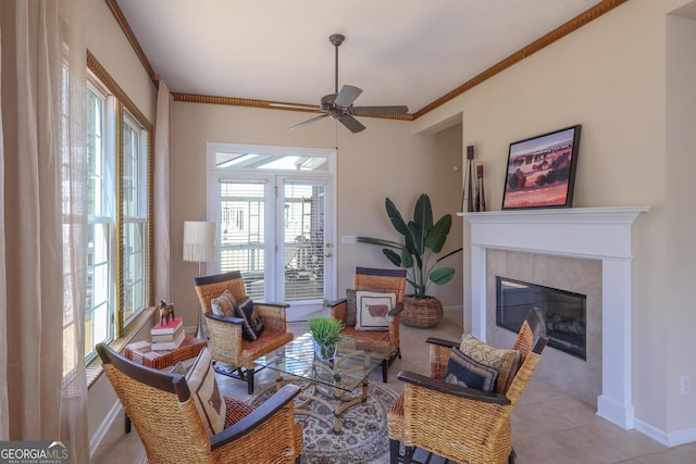 sitting room featuring plenty of natural light, ceiling fan, a tiled fireplace, light tile patterned floors, and crown molding