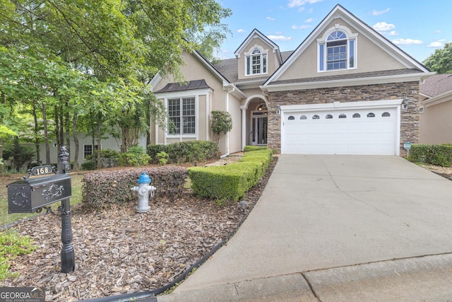 traditional-style house with stucco siding, stone siding, driveway, and a garage