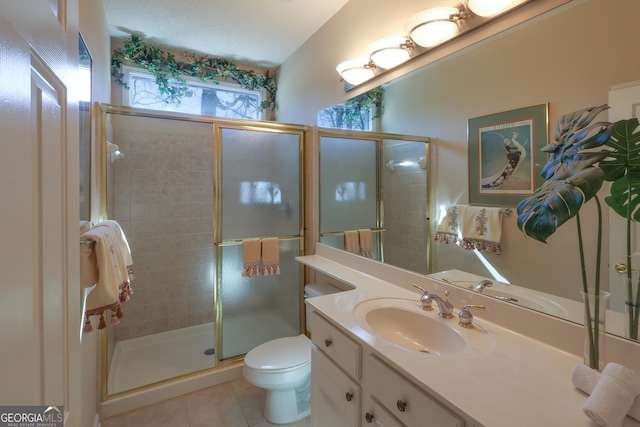 bathroom featuring tile patterned flooring, a stall shower, vanity, and toilet