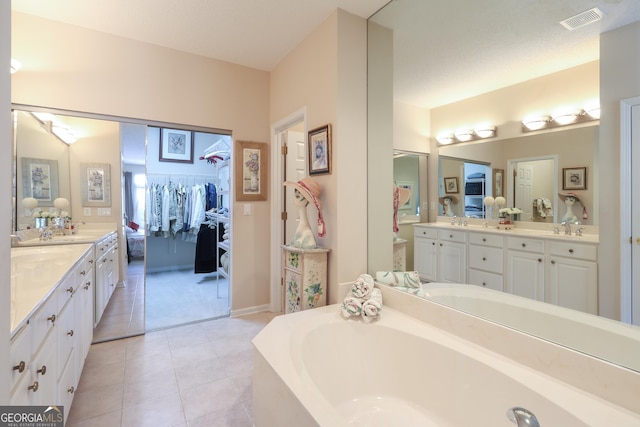 bathroom with a garden tub, vanity, tile patterned flooring, and a walk in closet
