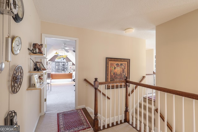 stairway with carpet, ceiling fan, and a textured ceiling