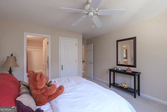carpeted bedroom with baseboards, a spacious closet, a ceiling fan, a closet, and a textured ceiling