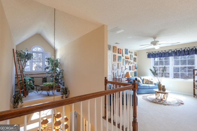 carpeted living area featuring a textured ceiling, ceiling fan, and lofted ceiling