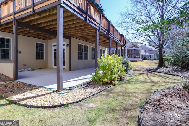 back of property with stucco siding, a deck, a patio, and a yard