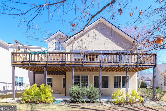 rear view of property with a wooden deck and stucco siding