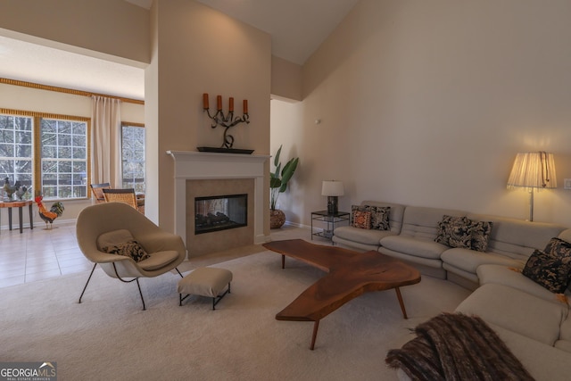 carpeted living area with tile patterned floors, baseboards, high vaulted ceiling, and a multi sided fireplace