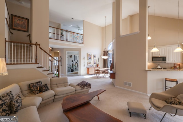 living room with high vaulted ceiling, light colored carpet, stairway, and baseboards