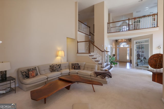 carpeted living room with a towering ceiling, stairway, and a notable chandelier