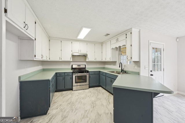 kitchen featuring gray cabinetry, a sink, under cabinet range hood, stainless steel range with gas cooktop, and a peninsula