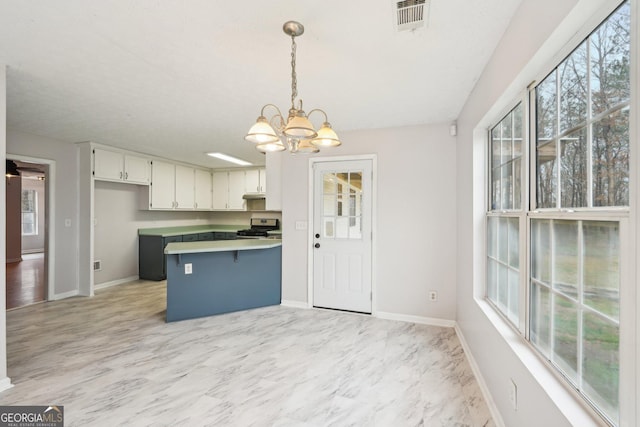 kitchen featuring decorative light fixtures, visible vents, gas range, and plenty of natural light