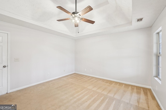 unfurnished room with visible vents, baseboards, a raised ceiling, and carpet