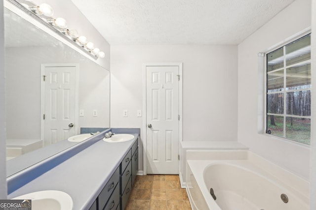 full bathroom with a sink, a textured ceiling, a bath, and double vanity