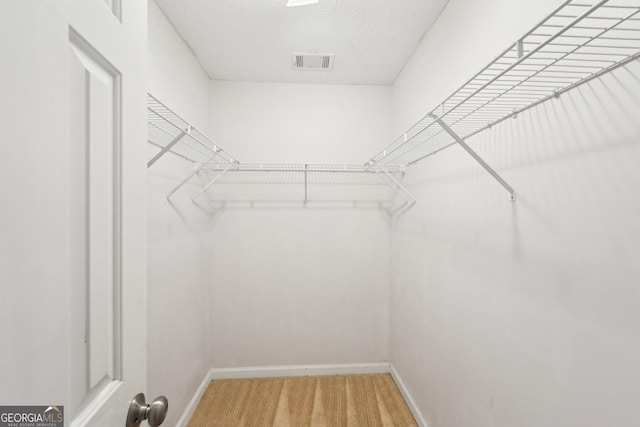 spacious closet with visible vents and light colored carpet