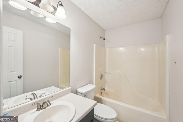 bathroom featuring toilet, a textured ceiling, vanity, and bathtub / shower combination