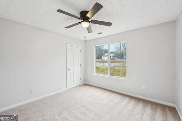 carpeted empty room with baseboards, visible vents, and a textured ceiling