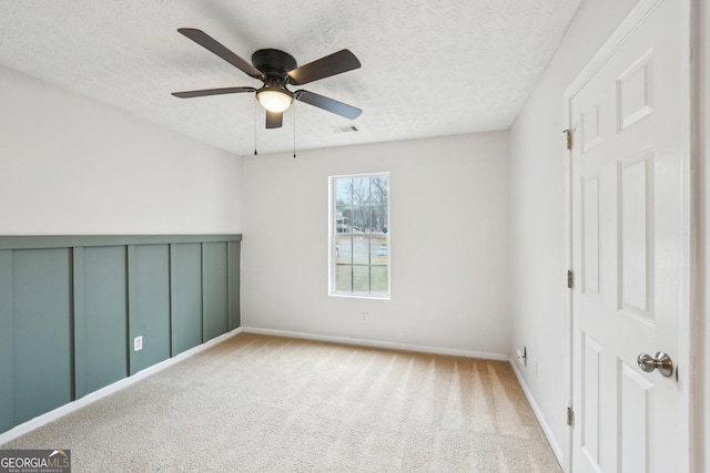 carpeted spare room featuring visible vents, a textured ceiling, and a ceiling fan