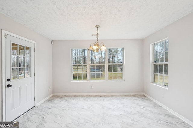 unfurnished dining area with visible vents, marble finish floor, a textured ceiling, an inviting chandelier, and baseboards