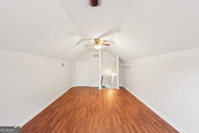 additional living space with wood finished floors, visible vents, baseboards, ceiling fan, and vaulted ceiling