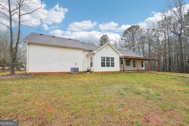 back of property with central AC unit, a yard, and fence