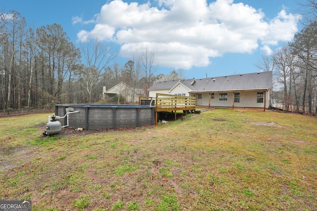 view of yard with fence, an outdoor pool, and a wooden deck