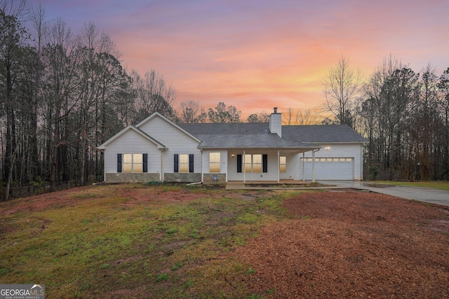 ranch-style house featuring a porch, an attached garage, a chimney, a front lawn, and concrete driveway