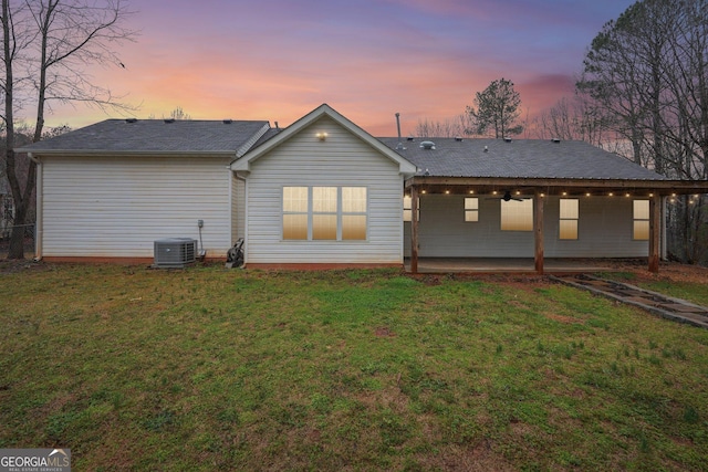 back of house featuring central air condition unit, a patio, and a lawn