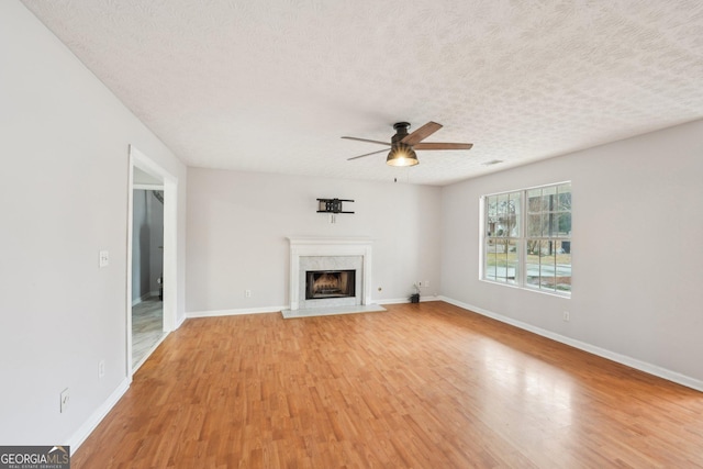 unfurnished living room with baseboards, a textured ceiling, light wood-style flooring, and a fireplace