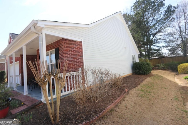 view of home's exterior with brick siding, a patio, and fence