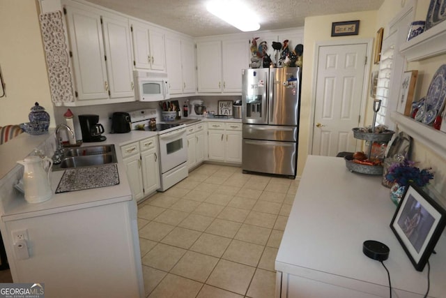 kitchen with light tile patterned floors, light countertops, a sink, a textured ceiling, and white appliances