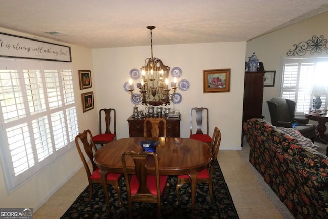 dining room featuring a healthy amount of sunlight, light tile patterned floors, a chandelier, and a textured ceiling